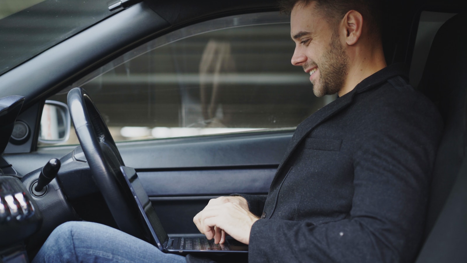 Man working on laptop inside a car